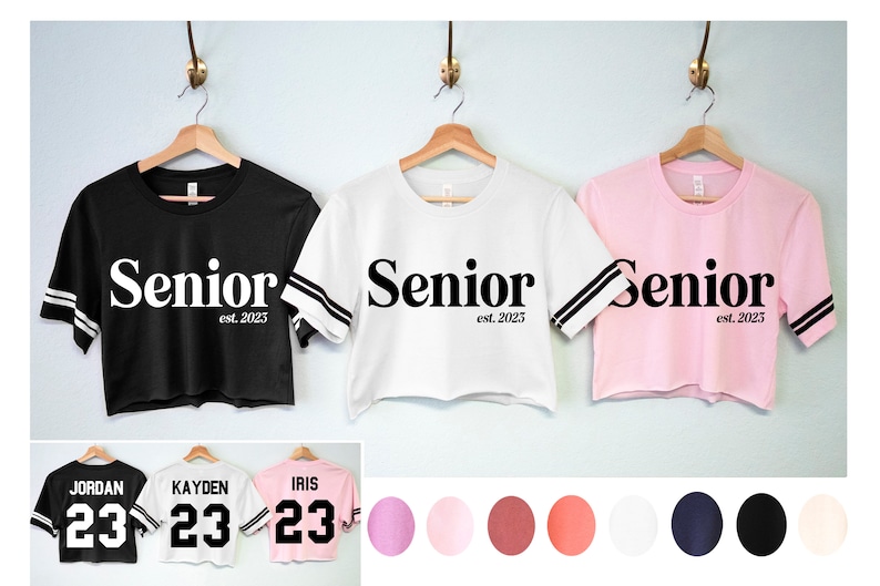 May include: Three cropped t-shirts with the word "Senior est. 2025" printed on the front. The shirts are black, white, and pink. Three additional t-shirts are shown with the number "23" printed on the back. The shirts are black, white, and pink. A colour palette of pink, white, red, and black is shown below the shirts.