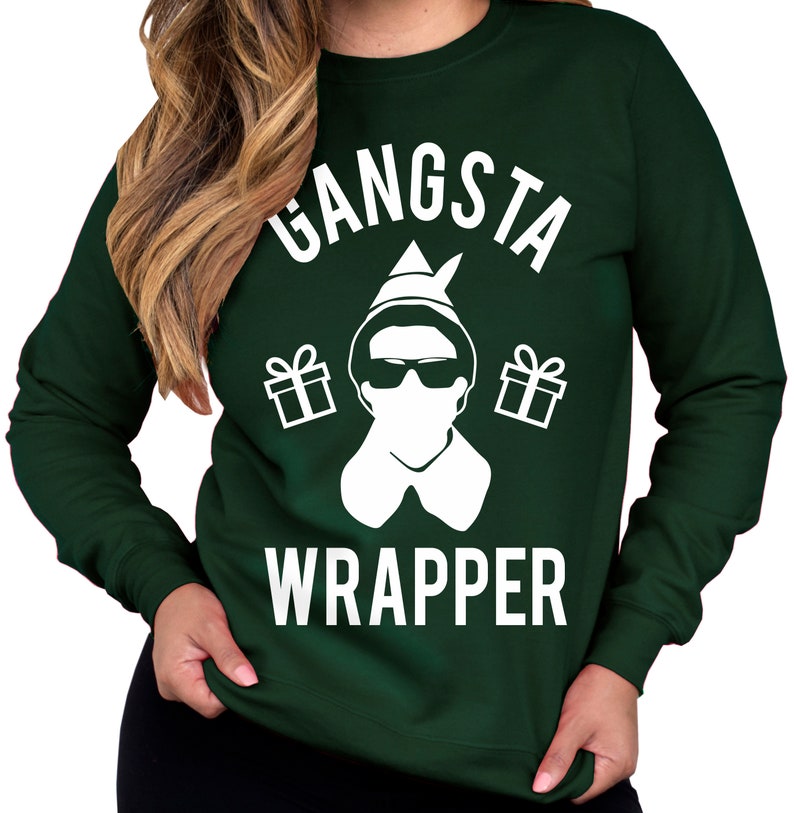 May include: A green sweatshirt with a white graphic of an elf wearing sunglasses and holding gifts. The text "Gangsta Wrapper" is printed on the sweatshirt.
