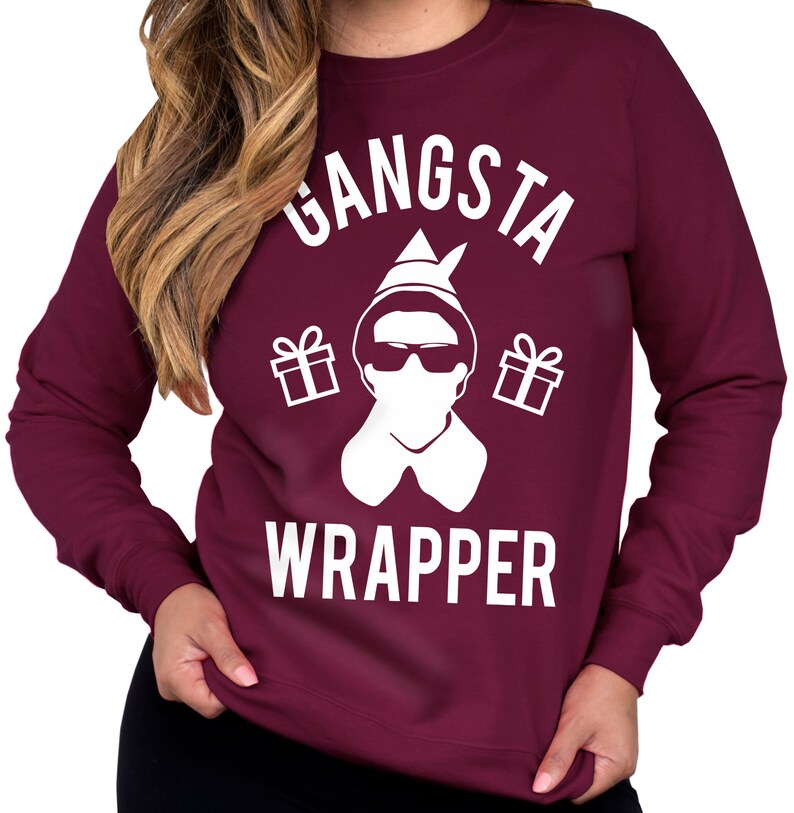 May include: Burgundy sweatshirt with a white graphic of an elf wearing sunglasses and a Santa hat. The graphic says "Gangsta Wrapper" with gift boxes on either side of the elf.