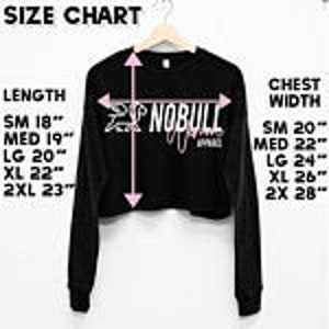 May include: Size chart for a black long-sleeve cropped shirt with the text "NOBULL" printed on the front. The chart shows measurements in inches for length and chest width in sizes small, medium, large, extra large, and 2 extra large.