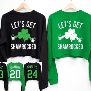 May include: Two black and green cropped sweatshirts with the text "Let's Get Shamrocked" and a shamrock with beer mugs. The sweatshirts have different numbers on the back: 03, 20, and 24.
