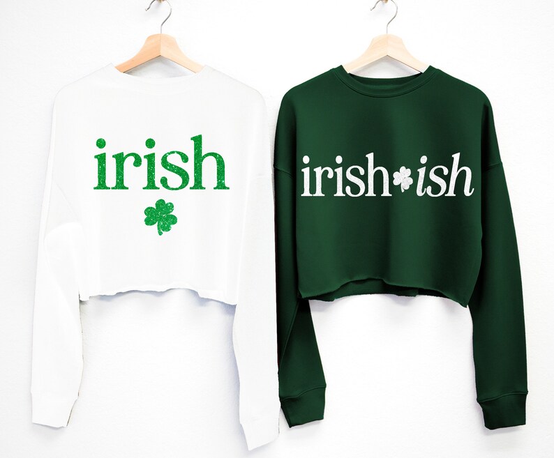May include: Two white long-sleeved cropped sweatshirts with green shamrock designs. One sweatshirt says "irish" and the other says "irish*ish".