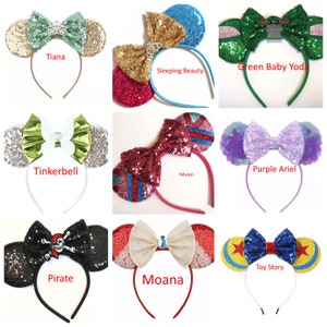 May include: A set of 10 Disney character-themed headband ears with sparkly bows. The characters include Tiana, Sleeping Beauty, Green Baby Yoda, Tinkerbell, Mulan, Purple Ariel, Pirate, Moana, and Toy Story.