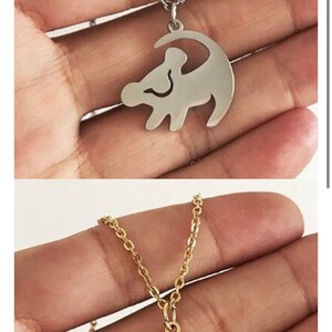 May include: Two necklaces with a lion king silhouette pendant. The necklace on top is silver and the necklace on the bottom is gold.