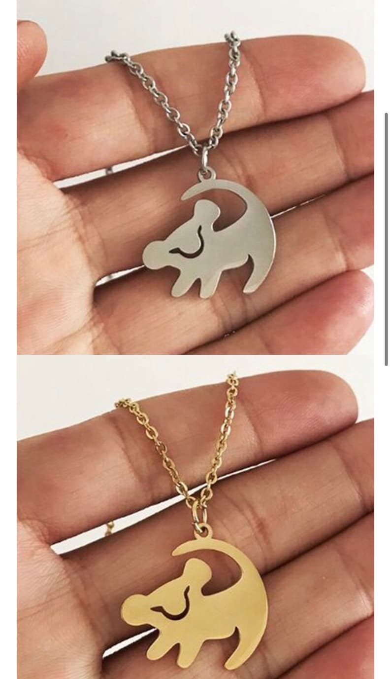 May include: Two necklaces with a lion king silhouette pendant. The necklace on top is silver and the necklace on the bottom is gold.