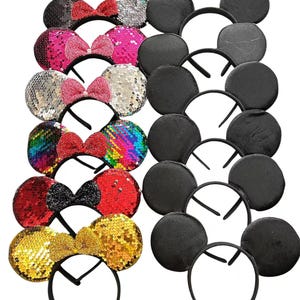 May include: A collection of headbands with sequined ears and bows in various colors, including black, pink, silver, and gold. Some headbands feature solid black ears. The bows are red, pink, and black.