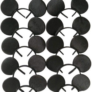 May include: A collection of black mouse ear headbands. Each headband features two large, round, black ears attached to a black plastic headband. The ears have a textured appearance. The headbands are arranged in a grid pattern.