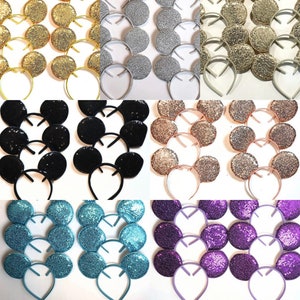 May include: A collection of sequined mouse ear headbands in various colors, including gold, silver, black, rose gold, teal, and purple. Each headband features a matching color scheme with the ears and headband.