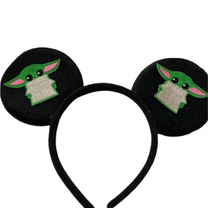 May include: Black headband with fuzzy, round ears featuring green and pink embroidered characters.