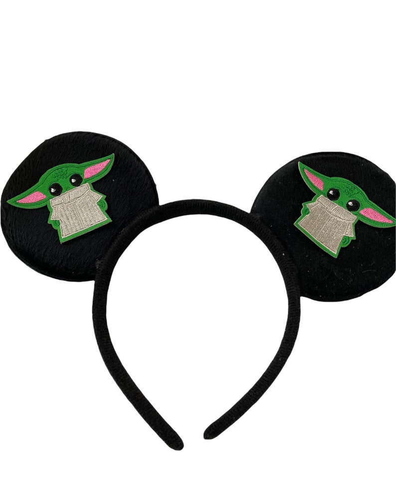 May include: Black headband with fuzzy, round ears featuring green and pink embroidered characters.