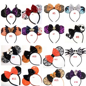 May include: Sixteen pairs of Halloween-themed Minnie Mouse ears with different designs, including a black and orange spiderweb design, a purple and black devil design, and a red and black bow design. Each pair of ears has a black headband.