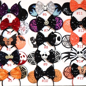 May include: Fifteen pairs of Halloween-themed Minnie Mouse ears with different designs, including a black and orange spiderweb, a black and white striped Jack Skellington, and a red and black Maleficent design. Each pair has a different number from 1 to 15.