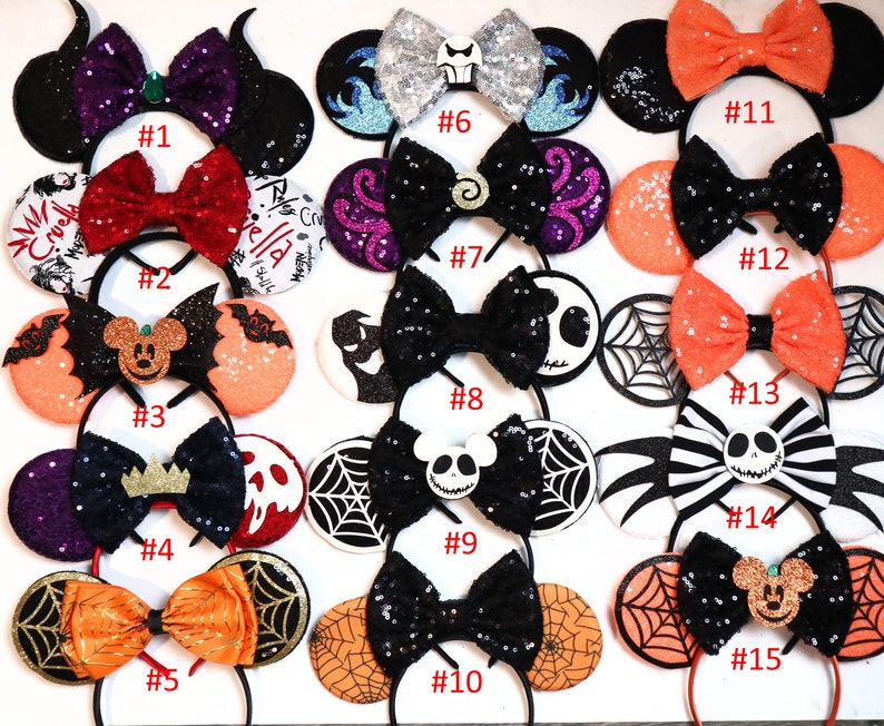 May include: Fifteen pairs of Halloween-themed Minnie Mouse ears with different designs, including a black and orange spiderweb, a black and white striped Jack Skellington, and a red and black Maleficent design. Each pair has a different number from 1 to 15.