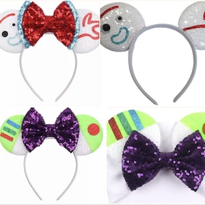 May include: A collection of character-themed headbands with sequined ears and bows. Designs include Buzz Lightyear, Forky, and an alien, with colors like green, purple, red, and blue. The headbands have silver bands.