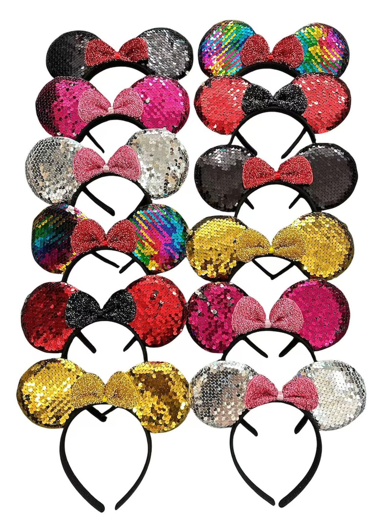 May include: A collection of sequined mouse ear headbands in various colors, including black, silver, pink, red, gold, and rainbow. Each headband features a matching bow. The headbands are on a black plastic frame.