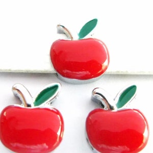 May include: Three red apple charms with green leaves. The charms are made of metal and have a shiny finish.