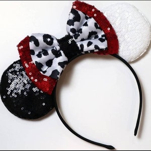May include: Black and white dalmatian print bow with red sequins on a black headband with black and white sequin ears and a white sequin ear.