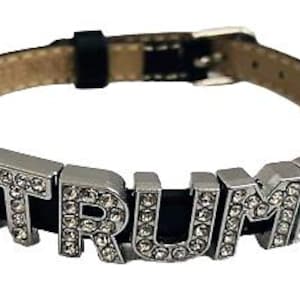 May include: A black leather bracelet with silver charms that spell out "TRUMP" in rhinestones.