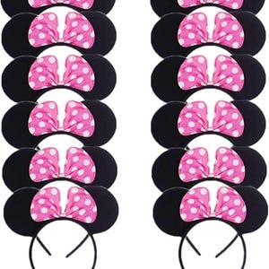 May include: Black mouse ear headbands with pink polka dot bows. The ears are round and the bows are a bright pink with white polka dots. The headbands are black and made of a flexible material. The image shows multiple headbands.