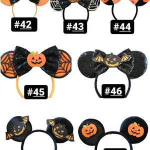 May include: Eight pairs of Halloween-themed Minnie Mouse ears. Each pair features a different design, including pumpkins, bats, and spiderwebs. The ears are black with orange and white accents. The numbers 42 through 48 are printed below each pair of ears.