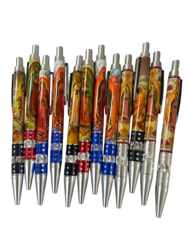 May include: A collection of ballpoint pens featuring religious imagery. The pens have silver tips and tops, with decorative bands in red, blue, and black. The pen barrels display colorful illustrations of religious figures.