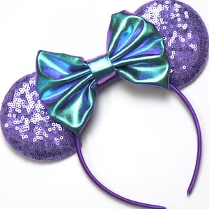 May include: Purple sequined mouse ears headband with a large iridescent green bow.