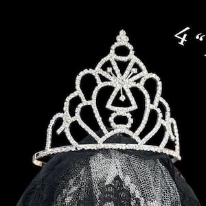 Pode incluir: Uma tiara prateada com strass transparentes, com cerca de 10 cm de altura, assenta sobre um v&eacute;u preto. A tiara apresenta um design vazado com uma forma geom&eacute;trica central e bordas curvas, ideal para casamentos.