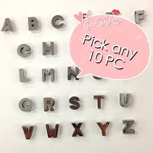 May include: A set of 26 silver letter charms, each letter of the alphabet is displayed in a grid. The letters are available for purchase in sets of 10. The text on the image reads "Pick any 10 PC".