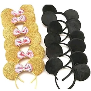 May include: A collection of headbands with mouse ears. One set features gold sequined ears with pink and white bow accents. The other set has solid black ears. Both sets have a thin, gold or black headband.