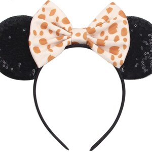 May include: Black sequined mouse ears headband with a brown and white spotted bow.