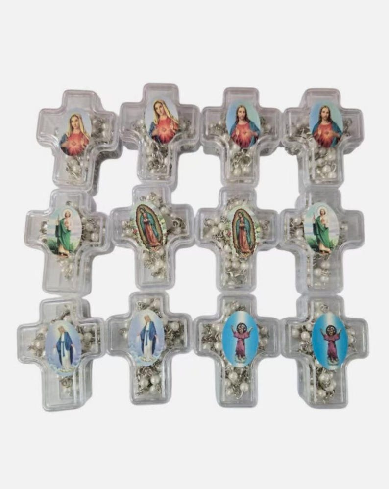 May include: A collection of clear plastic cross-shaped rosaries. Each cross features a religious image and a string of white beads. The images include depictions of religious figures in various colors.