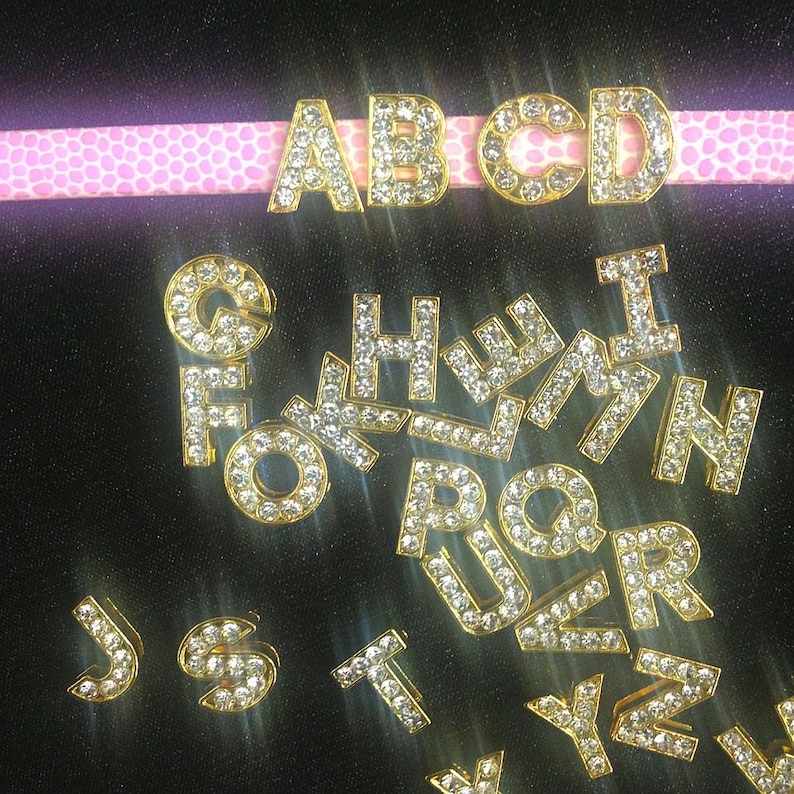 May include: Gold-toned alphabet letter charms with clear rhinestones. The letters A, B, C, D, F, G, H, I, J, K, L, M, N, O, P, Q, R, S, T, U, V, W, X, Y, and Z are visible.