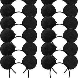 May include: A collection of black mouse ear headbands. Each headband features two round, black ears attached to a thin, black plastic band. The ears are made of a soft, felt-like material. The headbands are arranged in neat rows.