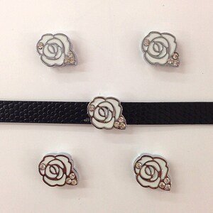 May include: Five white enamel rose charms with clear rhinestone accents. The charms are silver-toned and have a raised design.