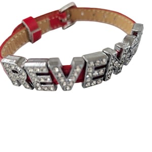 May include: Red leather bracelet with silver charms spelling out the word "REVENGE" with rhinestones.