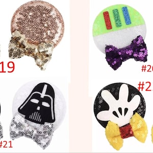 Puede incluir: Una colecci&oacute;n de diademas con orejas de rat&oacute;n con lentejuelas. Los dise&ntilde;os incluyen oro rosa, verde y blanco con un lazo morado, blanco y negro con un lazo plateado y un dise&ntilde;o de mano de Mickey Mouse con un lazo amarillo. Cada diadema tiene un n&uacute;mero.