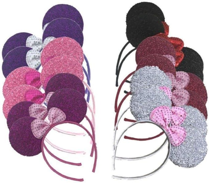 May include: A collection of headbands with large, round ears and sequined bows. The headbands come in various colors, including purple, pink, silver, and black. The ears are covered in glittery fabric.