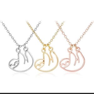 May include: Three necklaces with a sloth pendant. The necklaces are silver, gold, and rose gold.