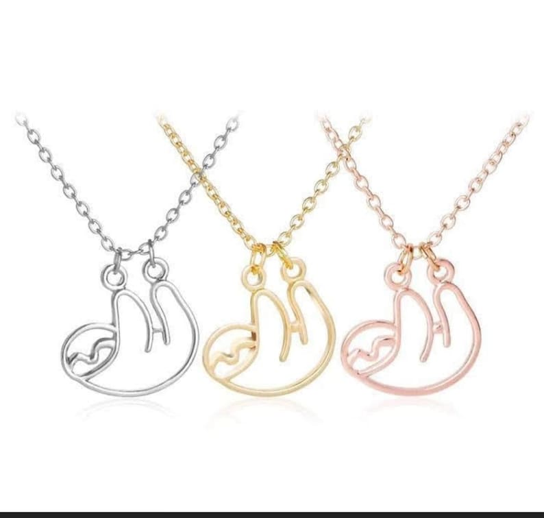 May include: Three necklaces with a sloth pendant. The necklaces are silver, gold, and rose gold.