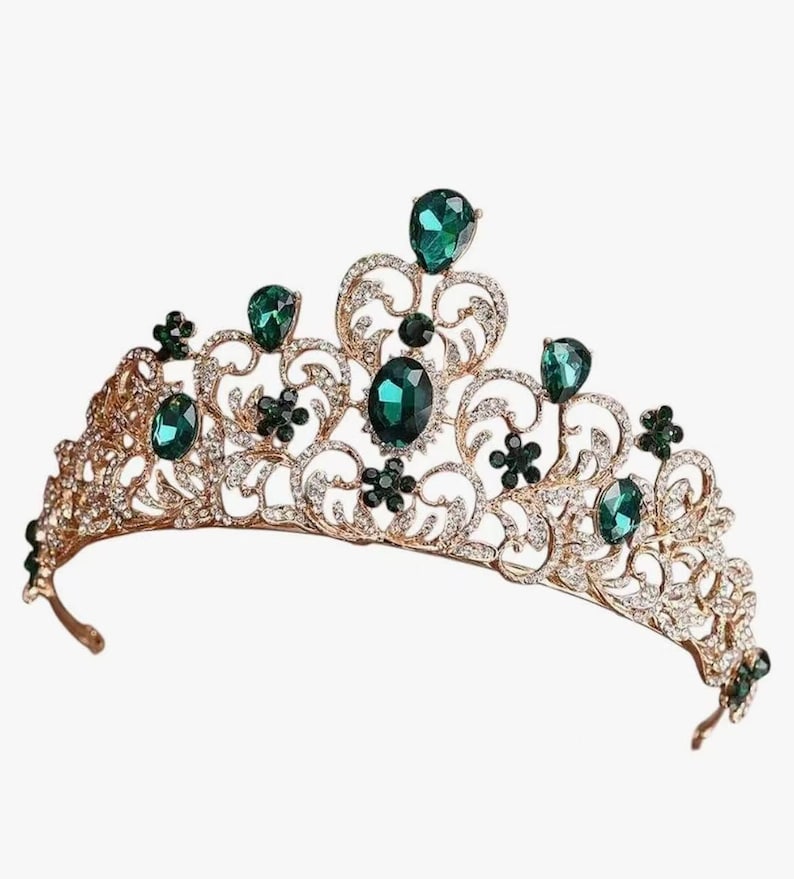 Pode incluir: Uma tiara dourada com pedras preciosas verde esmeralda e strass transparentes. A tiara apresenta um design ornamental de filigrana com pedras verdes ovais e em forma de gota. Para uma ocasi&atilde;o especial.