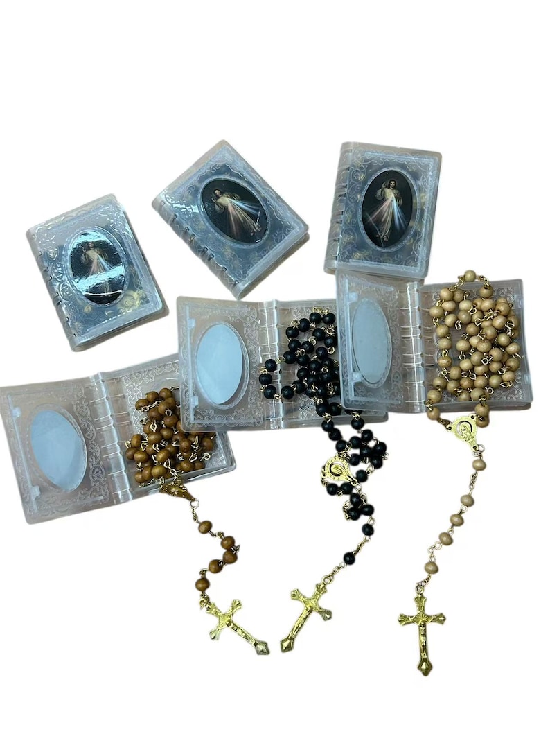 May include: Several rosaries with wooden and black beads, each with a gold-colored crucifix. The rosaries are displayed with small, clear plastic cases, some open and some closed, each featuring a religious image.