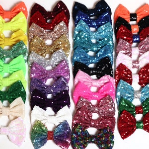 May include: A collection of 20 colorful sequined bows in various colors, including pink, blue, green, red, yellow, and white. The bows are arranged in rows and are all made of the same material.