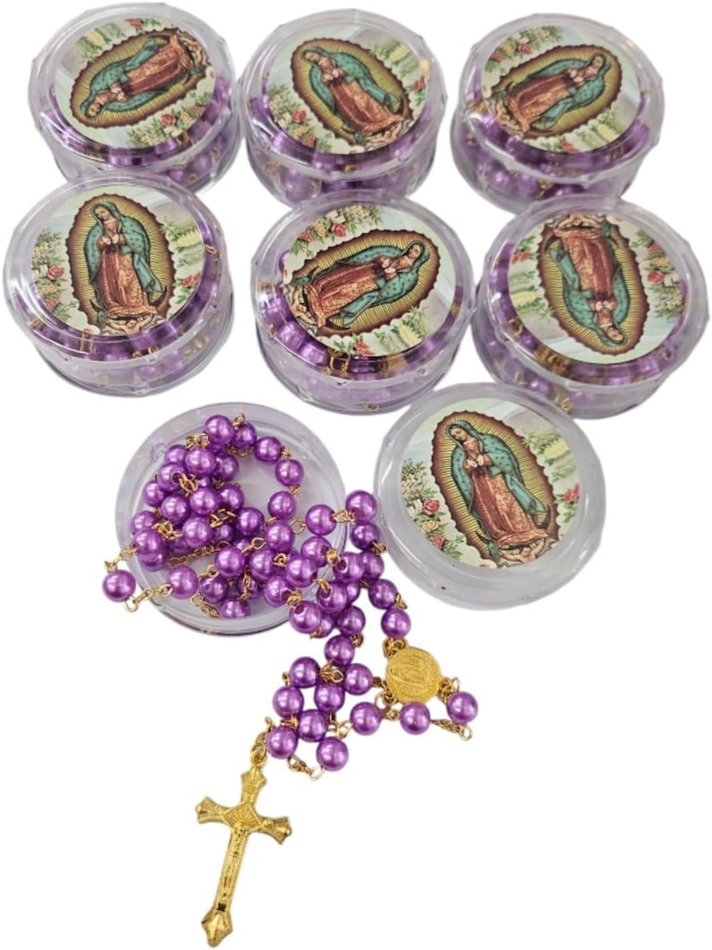 May include: A collection of purple beaded rosaries, with a gold-colored cross and medallion. The rosaries are displayed in clear plastic containers, each with a printed image of the Virgin Mary. The beads are a vibrant purple color.
