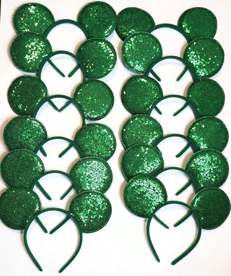 May include: A collection of green sequined mouse ear headbands. The ears are round and covered in shimmering green sequins. The headbands are a matching green color. The items are arranged in rows and columns on a white background.