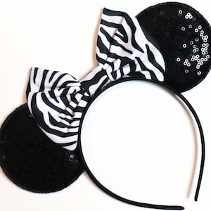 May include: Black headband with zebra print bow and black ears with silver sequins.