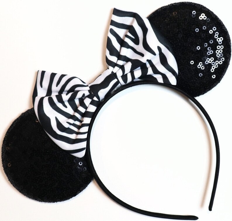 May include: Black headband with zebra print bow and black ears with silver sequins.