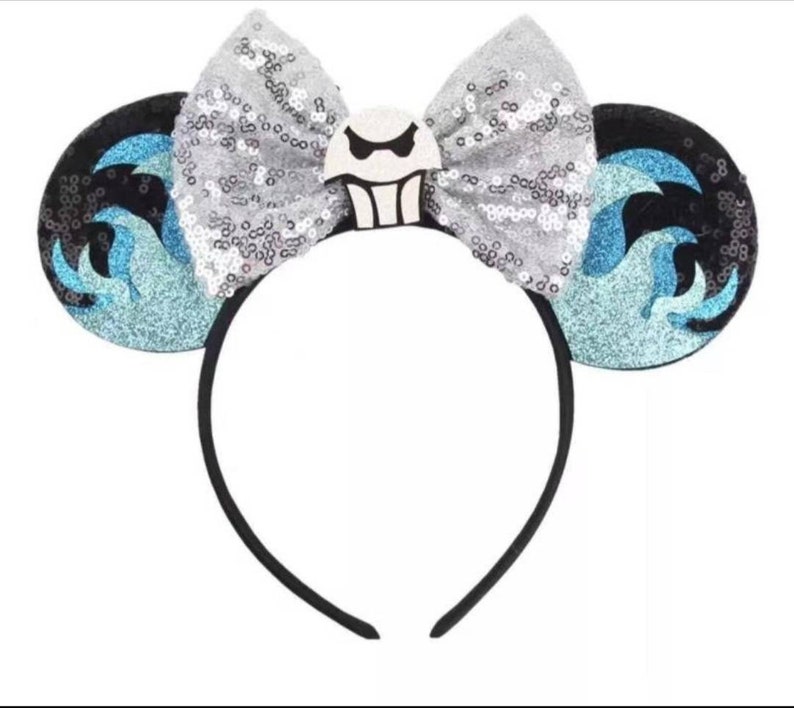 May include: Black headband with blue and silver sequined ears. The ears feature a white and black character with a ghost-like face.