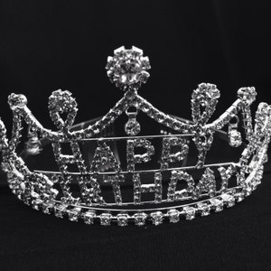 May include: A silver tiara with rhinestones spelling out "Happy Birthday".