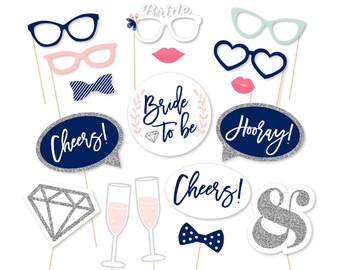 May include: A set of 12 photo booth props for a bridal shower or wedding. The props are printed on white cardstock with silver glitter accents and feature various designs, including glasses, lips, a bow tie, a diamond, champagne flutes, and speech bubbles with text like "Cheers!" and "Bride to be".