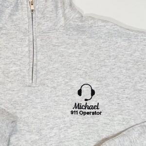 May include: A gray 1/4 zip sweatshirt with a black embroidered logo of a headset and the text "Michael 911 Operator".